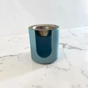 Brûle-parfum décoratif cylindrique vert avec ouverture frontale noire et coupelle supérieure.