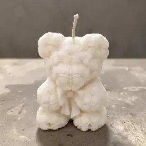 Bougie décorative blanche en forme d'ours composé de roses sculptées, avec nœud et mèche en coton, fabriquée à la main en France.