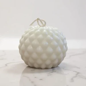 Bougie décorative blanche de forme sphérique, ornée de motifs arrondis en relief, avec une mèche nouée sur le dessus.